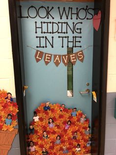 a door decorated with fall leaves and paper cutouts that read, look who's hiding in the leaves