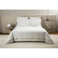 a bed with white sheets and pillows in a room