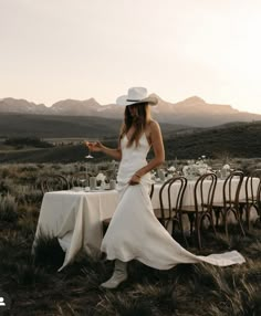 a woman in a white dress and hat sitting at a table