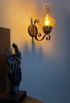 a light that is on the wall next to a statue with a lamp in it