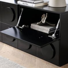 a black sideboard with two books and a lamp on it's end table