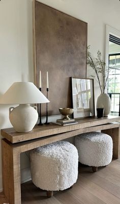 a console table with two stools and a lamp on it in a living room