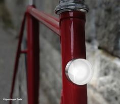 a close up of a red bike with a white light on the handlebars