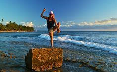 a woman jumping off a rock into the ocean