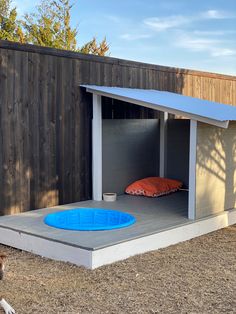 a dog laying in the grass next to a wooden fence with a pool on it