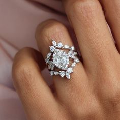 a woman's hand with a diamond ring on top of her finger and an engagement band