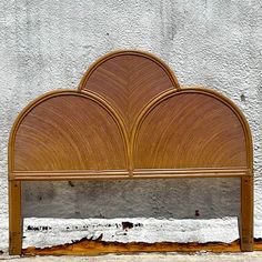 a wooden headboard on the ground next to a white and gray wall with an orange fire hydrant in front of it