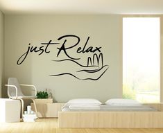 a wall decal that says just relax in black ink on a white wall next to a bed