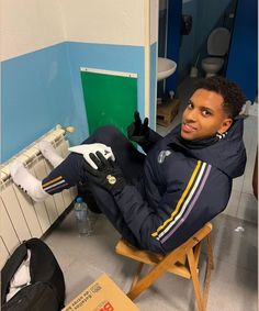 a man sitting in a chair with his feet on the back of a stool and wearing black gloves