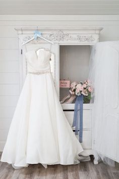 a wedding dress hanging in front of a white wardrobe