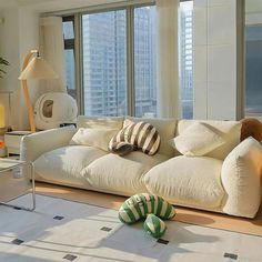 a living room filled with white furniture and tall buildings in the background at night time