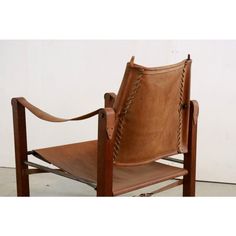 a brown leather chair sitting on top of a white floor next to a wooden frame