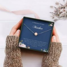 a person holding a box with a necklace in it that reads, the memory of your mother