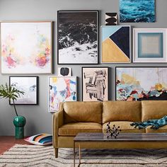 a living room filled with lots of pictures on the wall above a brown leather couch