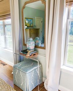 a living room with a mirror, stool and window