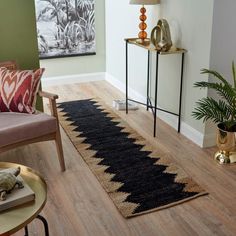 a living room with a rug on the floor next to a chair and table in front of a painting