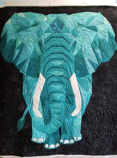 an elephant made out of paper sitting on top of a quilt