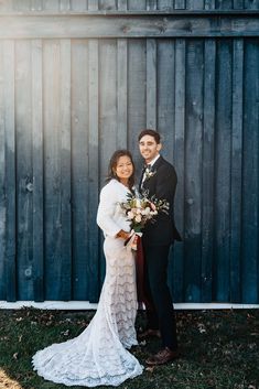 a bride and groom posing for a photo in front of a wooden fence at their wedding