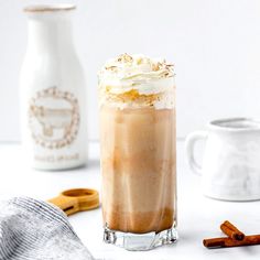 an iced drink with whipped cream and cinnamon sticks