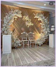 an image of a wedding stage set up with chairs and flowers on the wall behind it