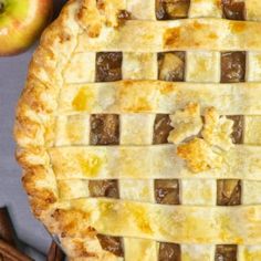 an apple pie sitting on top of a table next to cinnamon sticks