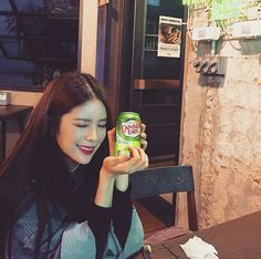 a woman sitting at a table with a can of beer