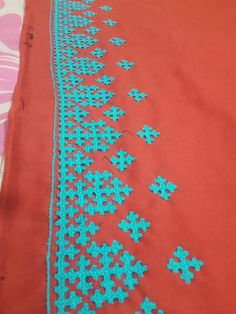 a red table cloth with blue flowers on it and a pink blanket in the background