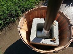 a pipe is in the middle of a wooden bucket with grass around it and dirt on the ground