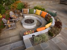 an outdoor fire pit surrounded by chairs and plants