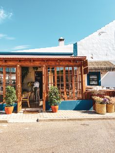 the outside of a restaurant with potted plants