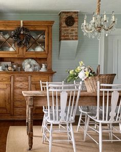 a dining room table with white chairs and a chandelier