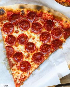 two slices of pepperoni pizza sitting on top of white paper