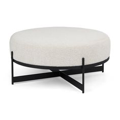 a round ottoman with black legs and a white upholstered cushion