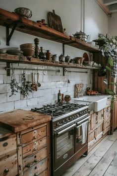 an old fashioned kitchen with wooden cabinets and white tile backsplash, wood flooring and open shelving