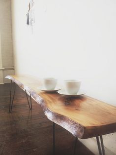 two white bowls are sitting on a wooden table in front of a window with hairpin legs