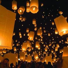 many lanterns are floating in the air at night