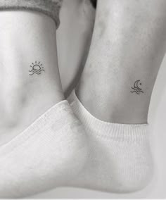 two people with matching tattoos on their feet, one is holding the other's leg