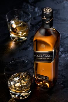 a bottle of whisky sitting next to a glass filled with ice