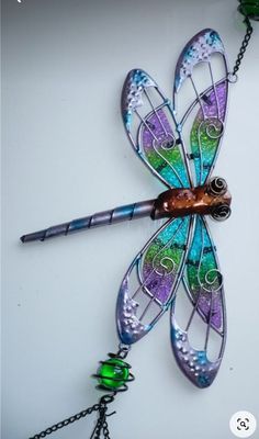 a colorful dragonfly is hanging on a chain