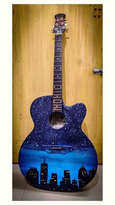 an acoustic guitar with a city skyline painted on it