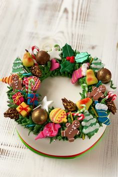 a cake decorated with christmas decorations on top of a white wooden table next to confetti and candies