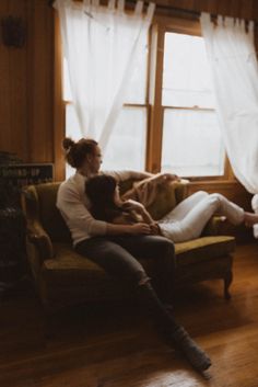 two people sitting on a couch in front of a window