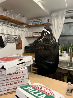 two pizza boxes stacked on top of each other in front of a woman with long black hair