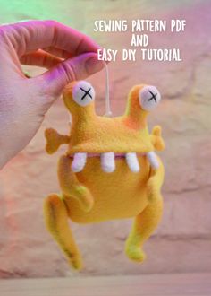 a hand is holding a sewing pattern for a stuffed animal toy that looks like a monster