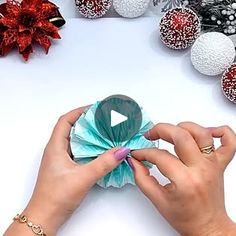 a woman is holding a green origami flower in front of other ornaments and decorations