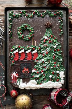 a decorated christmas tree and stockings on top of a cookie sheet with decorations around it