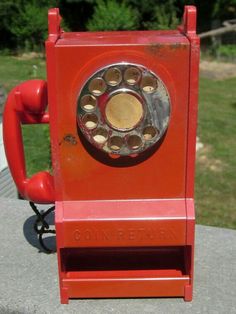 an old red phone sitting on top of a cement block