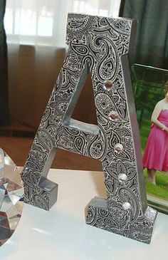 a silver metal letter sitting on top of a table next to a crystal ball and photo