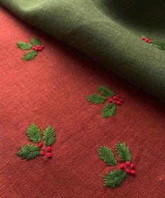 red and green fabric with holly leaves on it, next to a piece of cloth