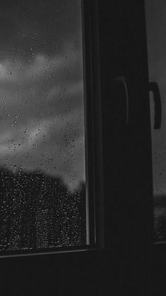 a window with rain drops on it and the sky in the back ground behind it